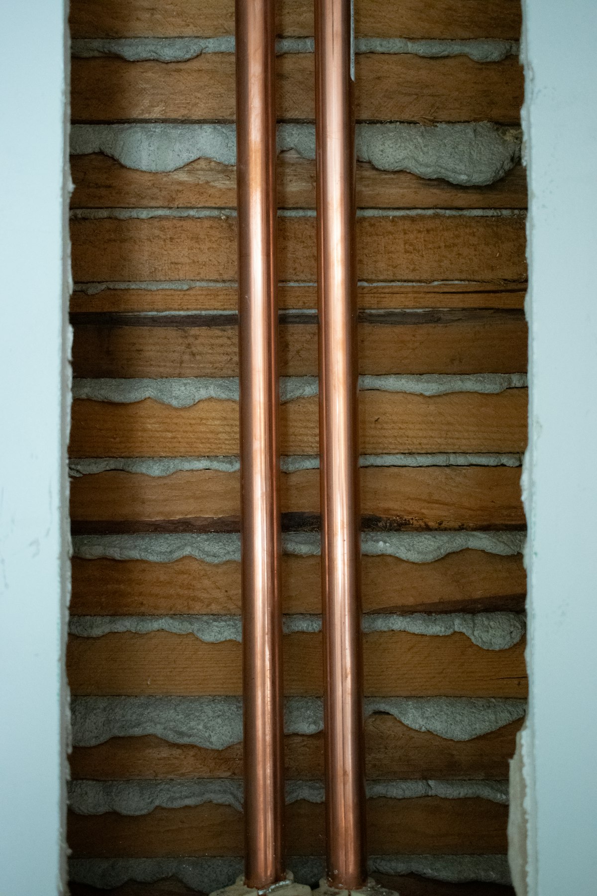 A pair of copper supply pipes mounted on an interior wall